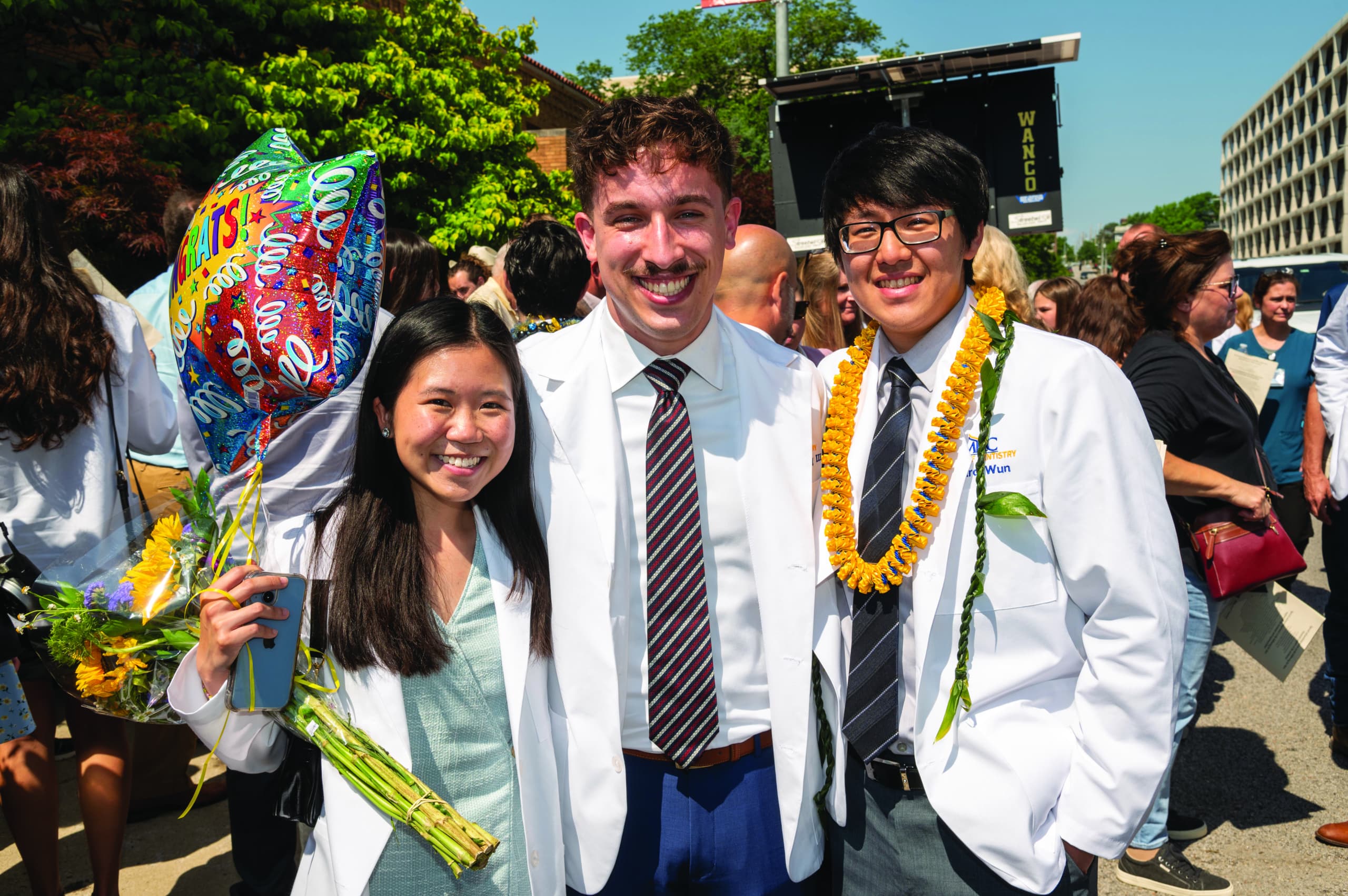 three dental students in white coats