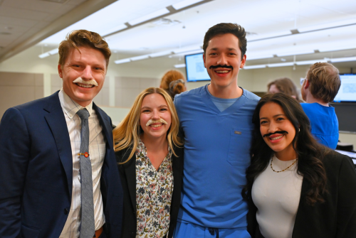 four people posing with mustaches